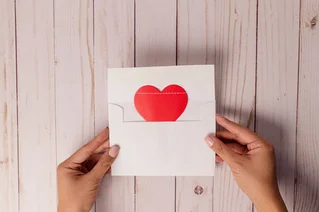 hands opening envelope with heart